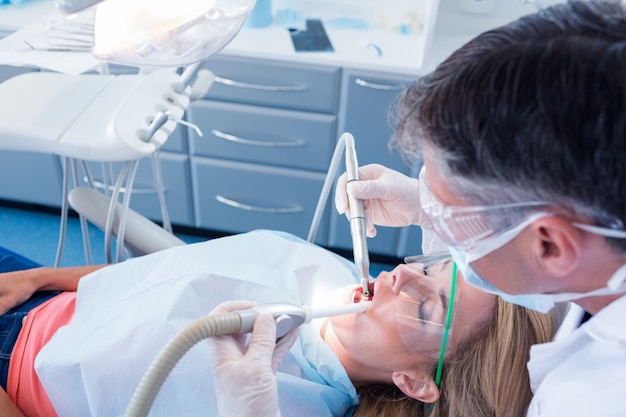 Dentist examining his patient with a suction hose