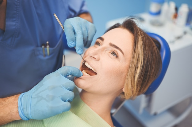 Dentist examining a patient's teeth using dental equipment in dentistry office