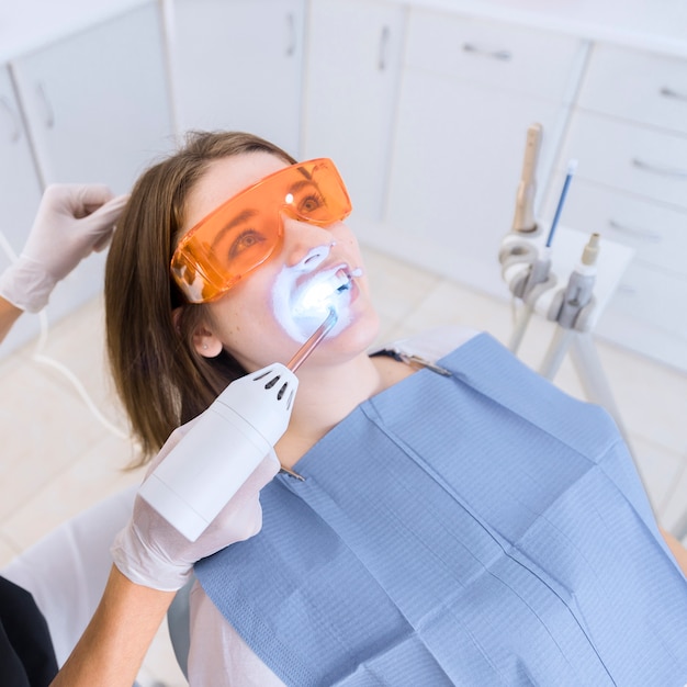 Dentist examining patient's teeth with dental uv light equipment