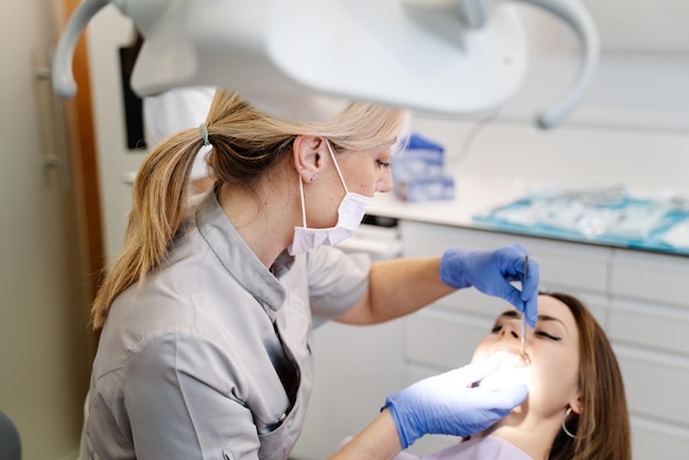 Dentist examining teeth of woman