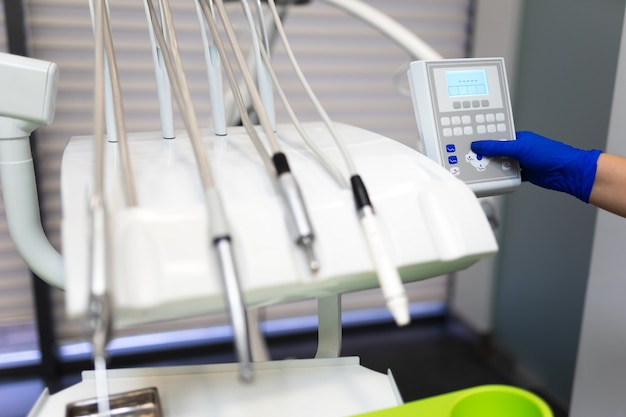 Dentist hand in glove press the control buttons of dental chair