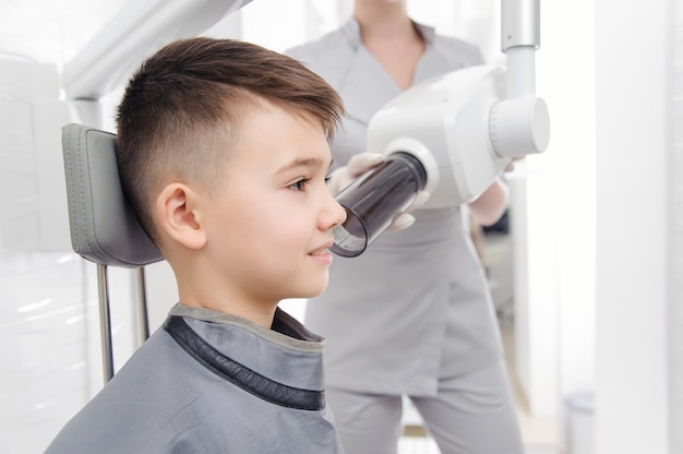 Dentist hands make jaw x-ray image for little boy in dental clinic