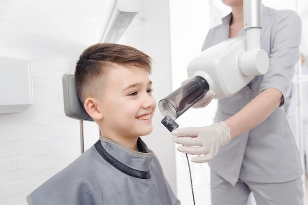 Dentist hands make jaw x-ray image for little boy in dental clinic