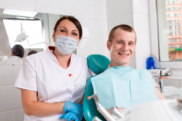 The dentist and her happy patient look at the camera and smile. Reception at the dentist, healthy teeth, happy patient, beautiful teeth.