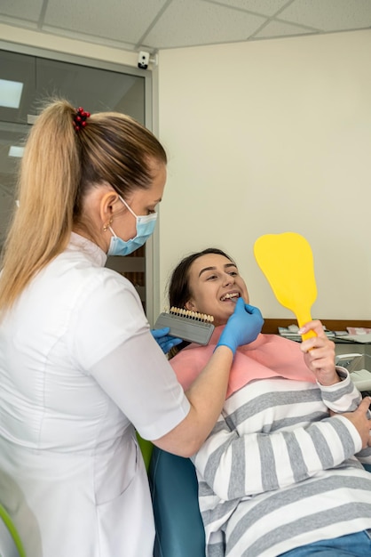 Dentist hold samples for bleaching treatment choosing shade to her patient