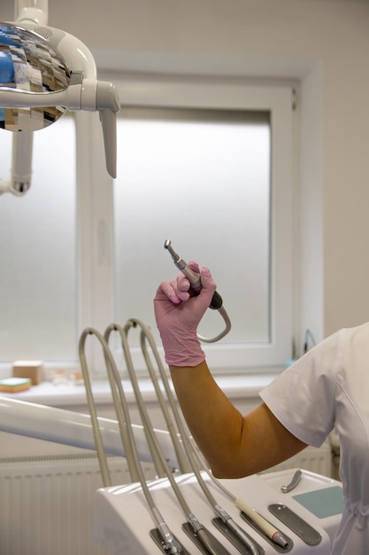 The dentist holds a drill in his hands.