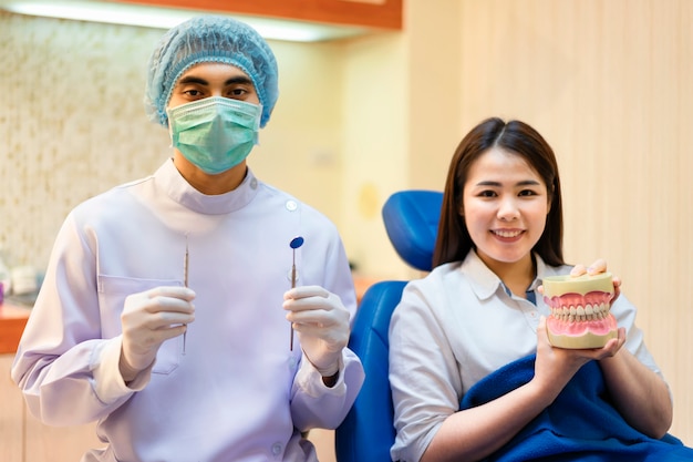 Dentist is holding model teeth on hand.