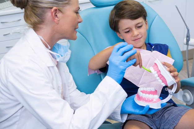 Dentist looking at boy brushing dentures