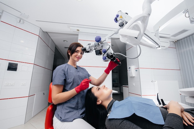 The dentist looks through a microscope and performs surgery on the patient