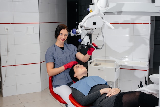 The dentist looks through a microscope and performs surgery on the patient