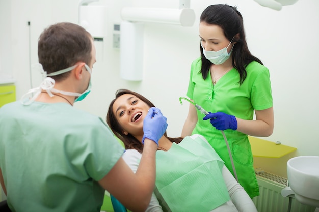 The dentist man are treating teeth to client in dental office