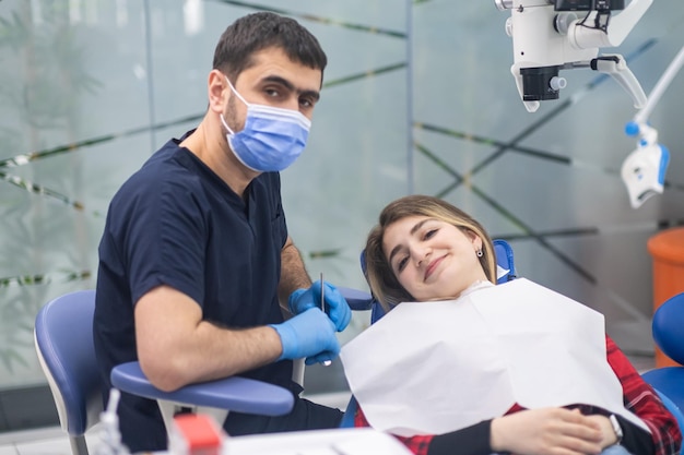 Dentist in medical mask and happy female patient smiling looking in camera