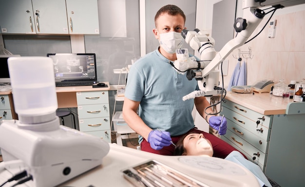 Dentist in medical mask treating woman teeth in dental office