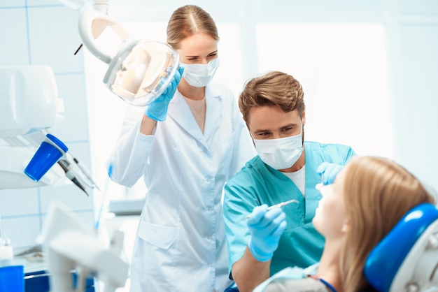 A dentist and a nurse treat a patient in a dental office.