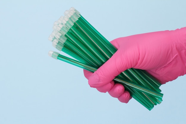 Dentist's hand in a rubber glove with saliva ejectors on blue background. Medical tools concept.