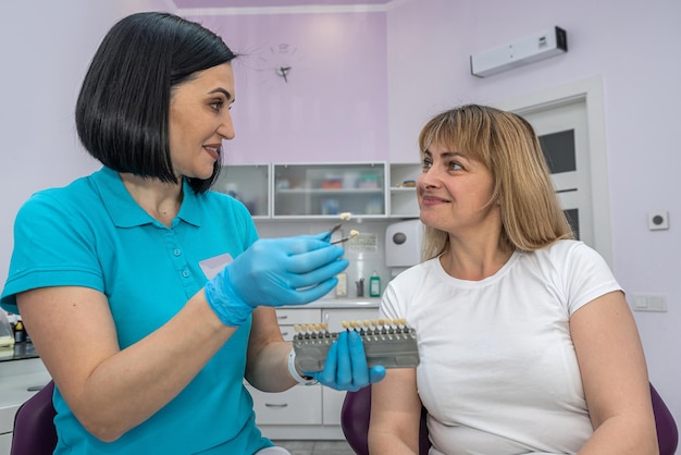 The dentist selects the tone of the patient's white teeth with a pallet