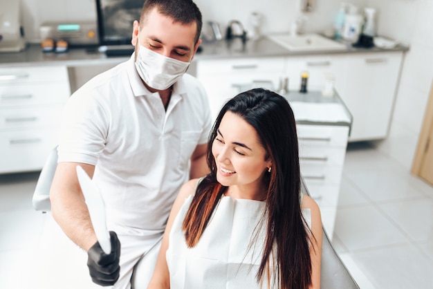 Dentist showing for the happy patient result of treatment