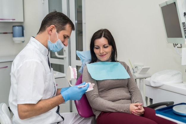 Dentist showing how to clean teeth right to patient