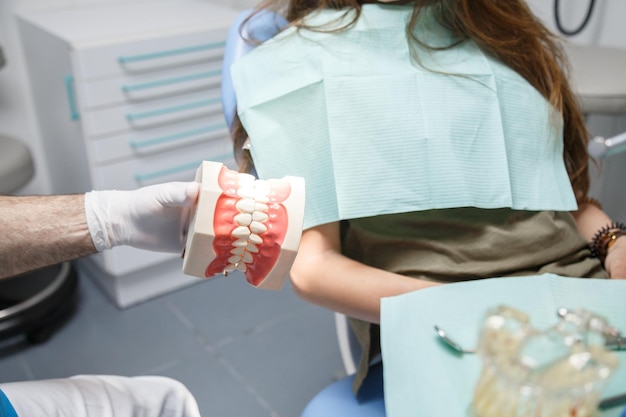 Dentist showing teeth cleaning technique to client.