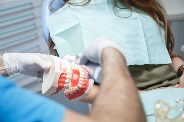 Dentist showing teeth cleaning technique to client.