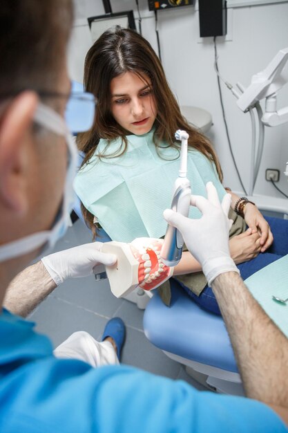 Dentist showing teeth cleaning technique to client.