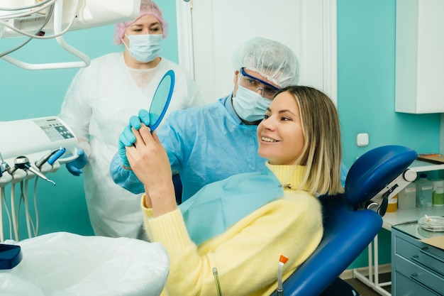 The dentist shows the client the results of his work in the mirror.