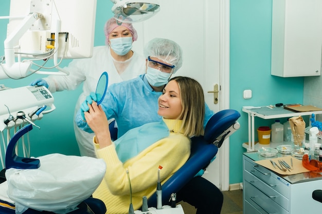 The dentist shows the client the results of his work in the mirror.