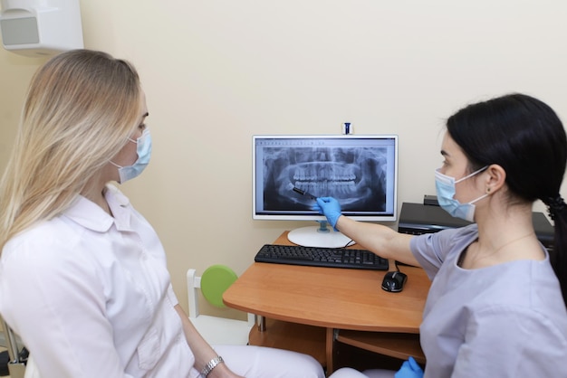 The dentist shows the patient an xray image on the monitor