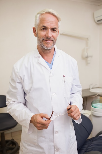 Dentist smiling at camera beside chair