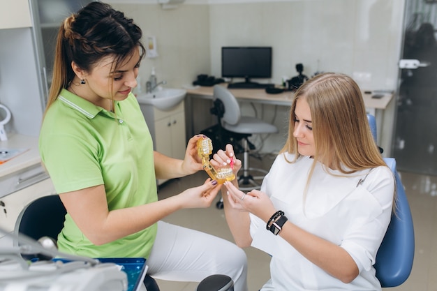 The dentist teaching a girl oral hygiene on braces in a dental clinic.