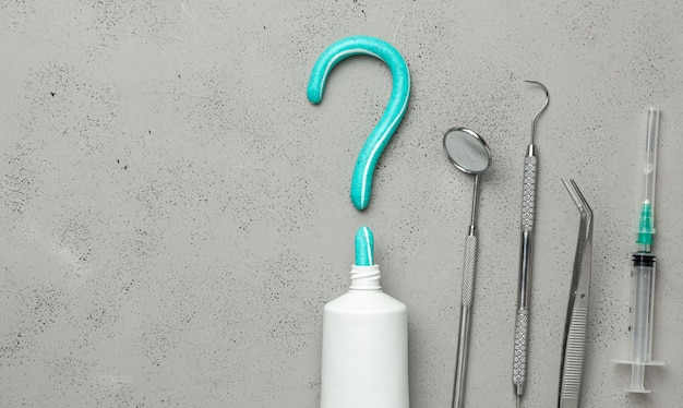 Dentist tools and toothpaste in the shape of question mark Mirror hook tweezers and syringe tools