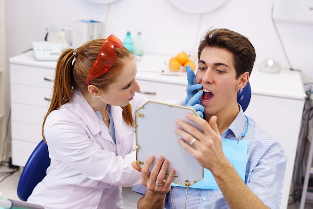 Dentist touching teeth of patient with mirror