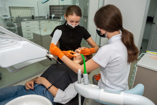 Dentist treats caries tooth female patient 
at dental clinic office.