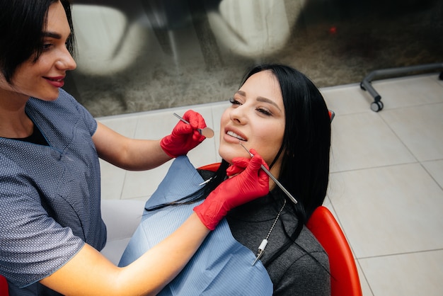 The dentist treats the girl's teeth to the patient. Dentistry