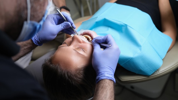 Dentist treats teeth with caries to female patient in dental clinic