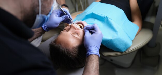 Dentist treats teeth with caries to female patient in dental clinic