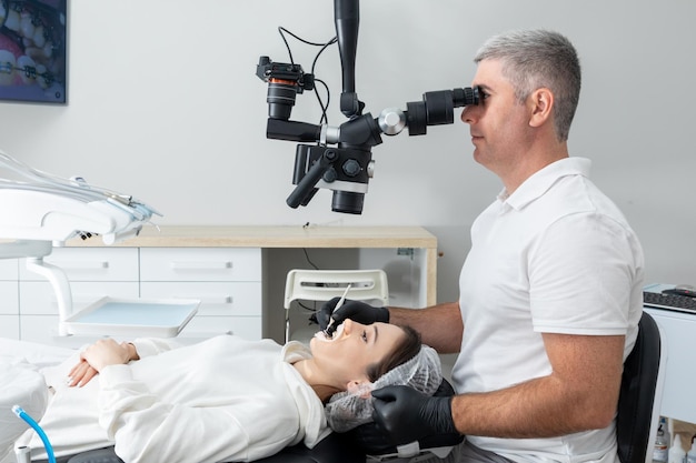 Dentist using dental microscope treating patient teeth at dental clinic office Medicine dentistry and health care concept Dental equipment