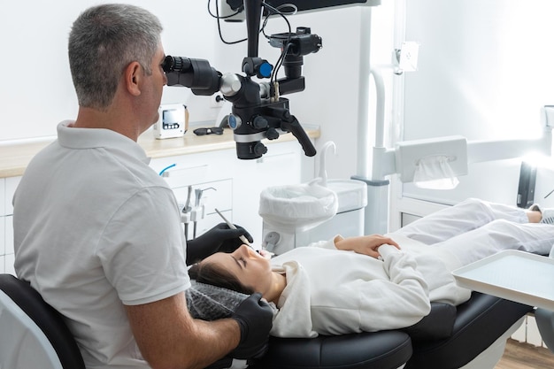 Dentist using dental microscope treating patient teeth at dental clinic office Medicine dentistry and health care concept Dental equipment