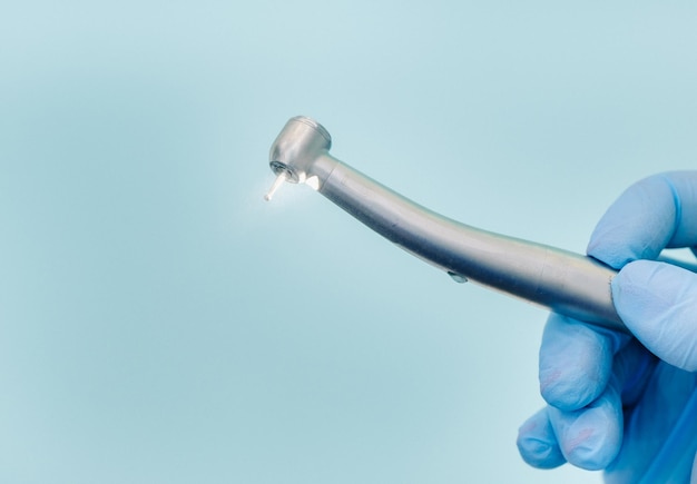 A dentist wearing gloves in the dental office holds a tool before working