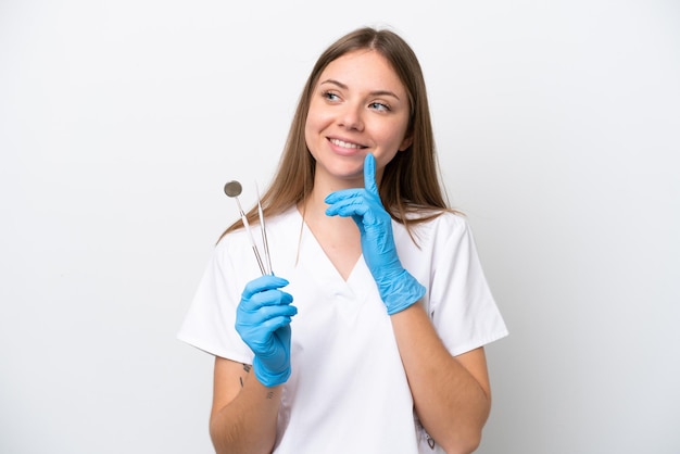 Dentist woman holding tools isolated on white background thinking an idea while looking up