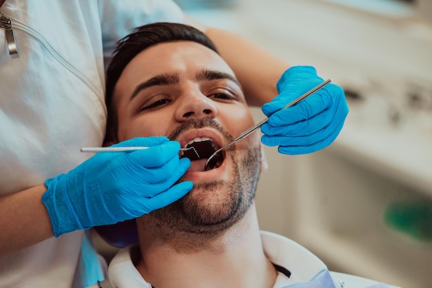 Dentist woman nurse checking patient mouth analyzing teeth infection using stomatological drill instrument during orthodontic examination in dental office room. Concept of dentistry procedure. High qu