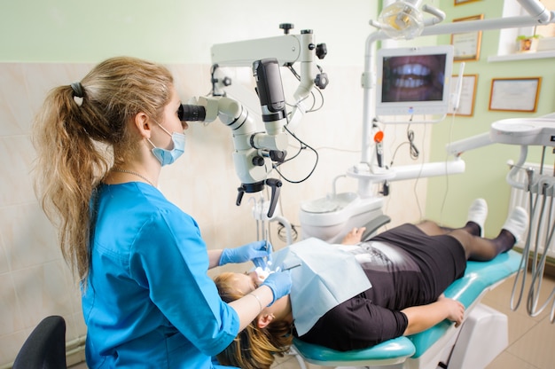 Dentist working with microscope at modern dentist office