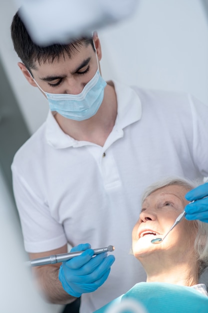 At the dentists. Male dentist working with a senior patient with periodental disease