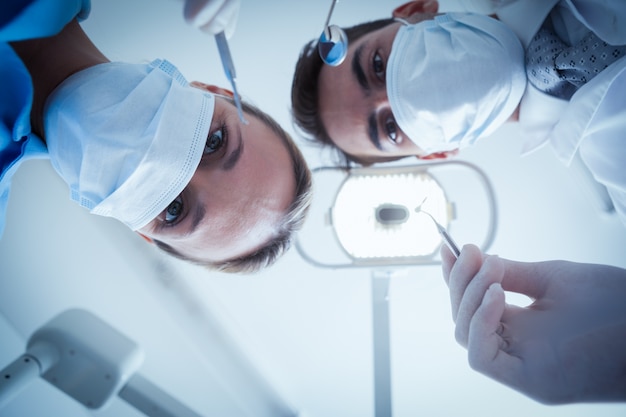 Dentists in surgical masks holding dental tools