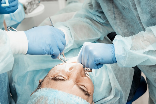 Dentists will perform an operation, implant placement. Real operation. Tooth extraction, implants. Professional uniform and equipment of a dentist. Healthcare Equipping a doctor workplace. Dentistry