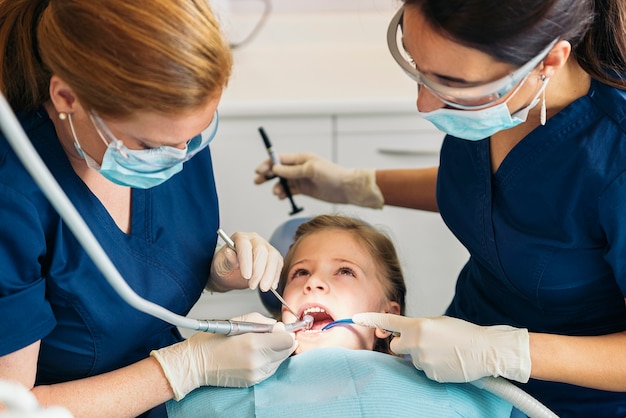 Dentists with a patient during a dental intervention to girl.