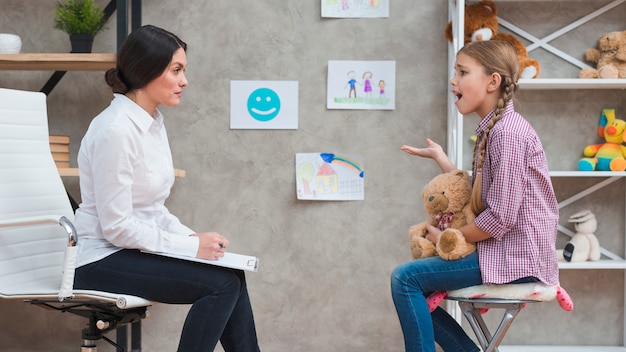 Depressed girl sitting in front of female psychologist talking with her