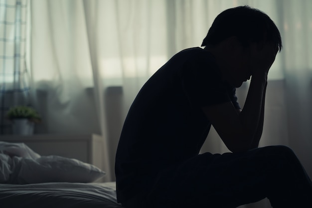 Depressed lonely man sitting alone on the bed