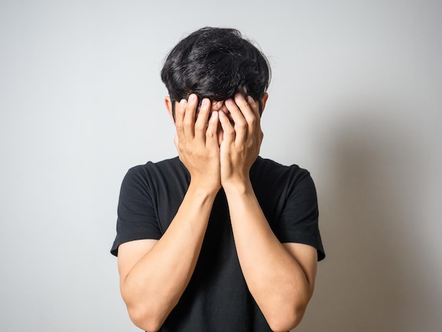 Depressed man hold his face feels hopeless white background