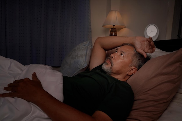 Depressed old man and stressed lying in bed from insomnia